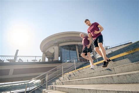 Young Male And Grey Haired Male Exercising Running Down Stairs Stock