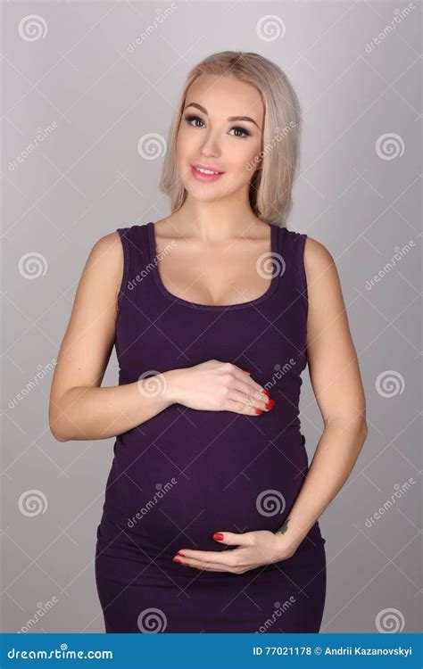 Pregnant Lady In A Dress Hugging Her Tummy Close Up Gray Background