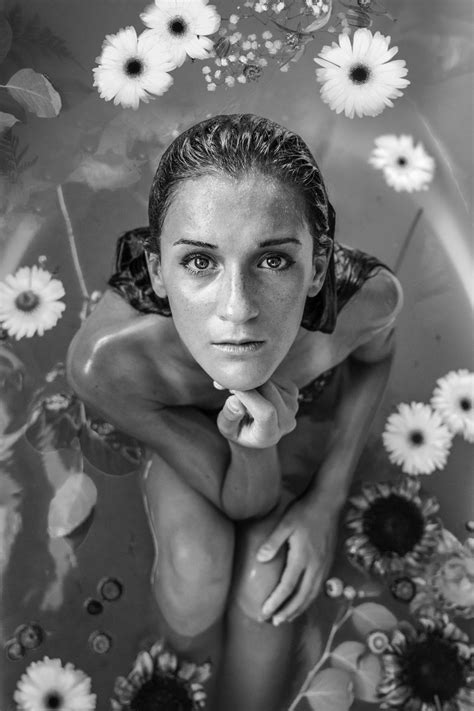 A Black And White Shot Of A Woman Sitting In A Bath Filled With Water And Flowers Woman In