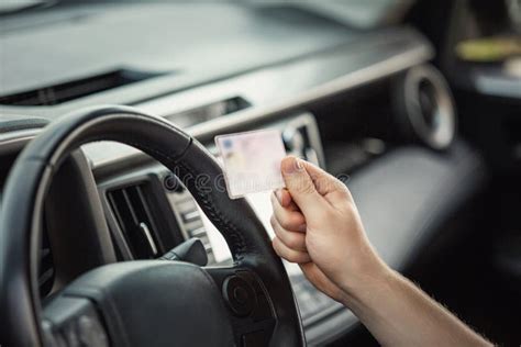 Close Up Person Hand Holding The Driver License In Front Of The