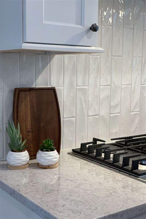 A Kitchen Counter With A Potted Plant On It And A Wooden Cutting Board