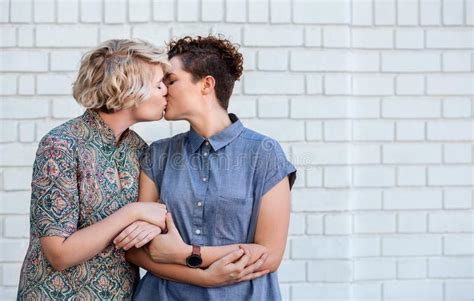 houdend van jong lesbisch paar die zich buiten het delen van een kus bevinden stock afbeelding