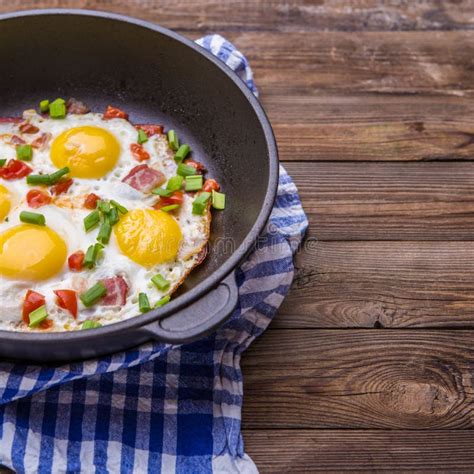 Fried Eggs In Pan With Tomatoes And Green Fresh Onion Stock Photo