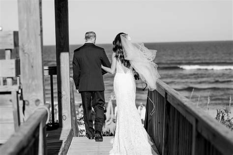 The Bride And Groom Are Walking Down The Pier