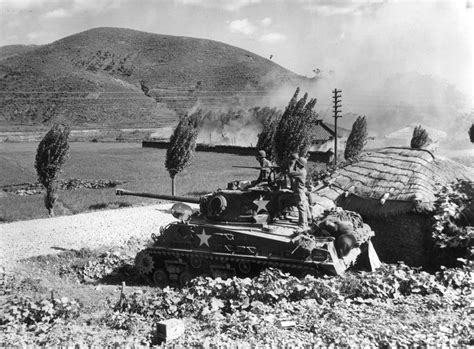 An American Army Tank Firing On Enemy Positions In The Area Around