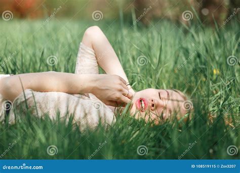 Outdoor Portrait Of Beautiful Blonde Girl Lying On Green Grass Stock