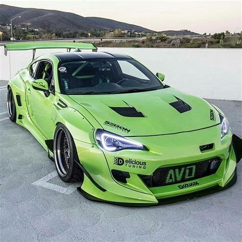 A Bright Green Sports Car Parked In A Parking Lot Next To A White Wall