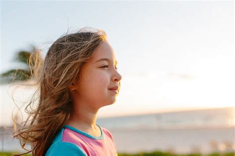 Cute Young Girl Enjoying The Wind Blowing In Her Face On The Beach By Stocksy Contributor
