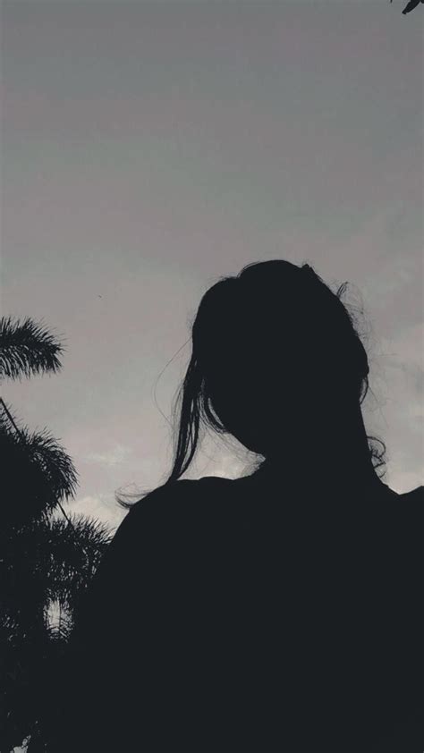 The Silhouette Of A Woman With Her Hair Blowing In The Wind Looking Up