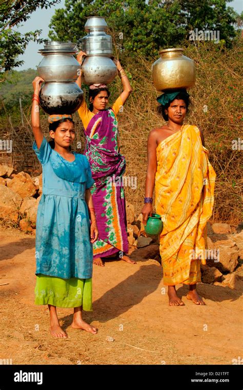 colourful tribeswomen carrying traditional water pots at a village near jeypore in southern