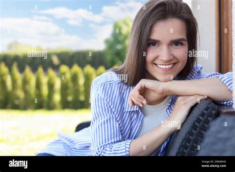 Portrait Of Beautiful Young Woman Sitting On Chair At Backyard Space