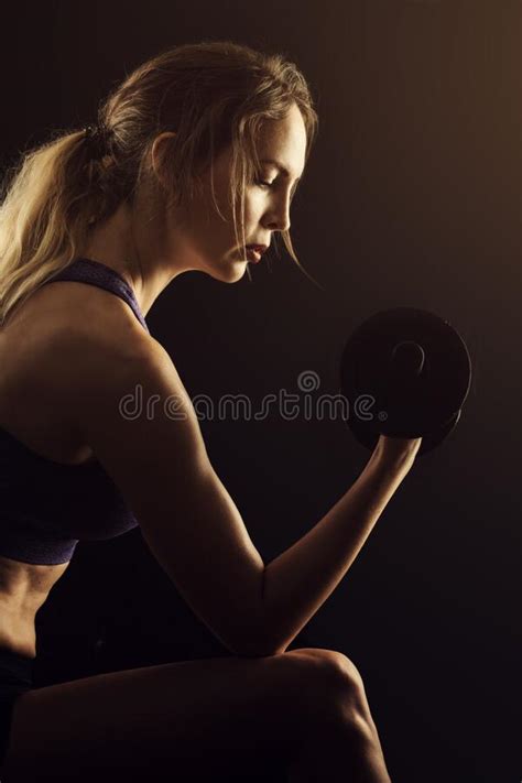 Slim Athletic Woman Holding Dumbbell In The Hand On Black Stock Photo