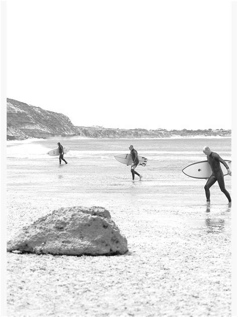 Three Surfers Are Walking On The Beach With Their Surfboards In Hand