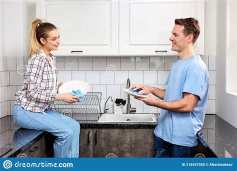 Positive Caucasian Woman Wiping Dishes While Husband Washing At Kitchen