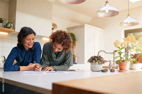 Same Sex Mature Female Couple Reviewing Domestic Finances And Investments In Kitchen At Home