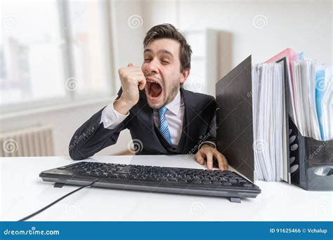 Young Sleepy And Tired Man Is Yawning At Work In Office Stock Photo