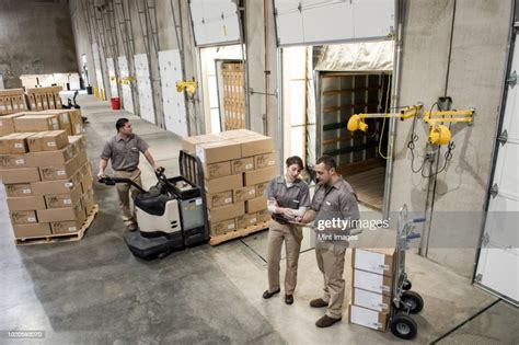 A Team Of Three Mixed Race Uniformed Warehouse Workers Loading Boxed