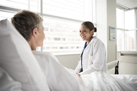 Female Doctor In Hospital Consulting With Senior Patient Main Certification Site