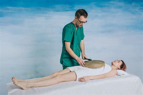 A Massage Therapist In Glasses And A Green Uniform Does Massage The Back Of A Beautiful Woman