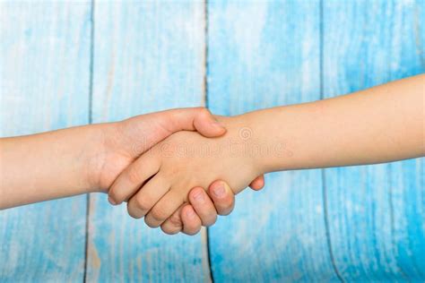 Friendly People Shaking Hands On A Blue Wooden Background Stock Photo