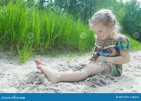 Little Girl Playing On Beach Dune And Burying Herself In White Sand At
