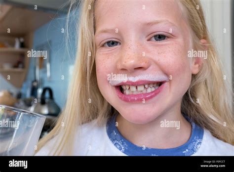 Young Blonde Caucasian Girl Drinking Milk With A White Milk Moustache