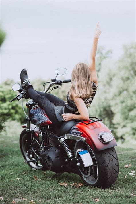 Blond Biker Girl Sitting On A Motorcycle And Raised Her Hand Up Rear