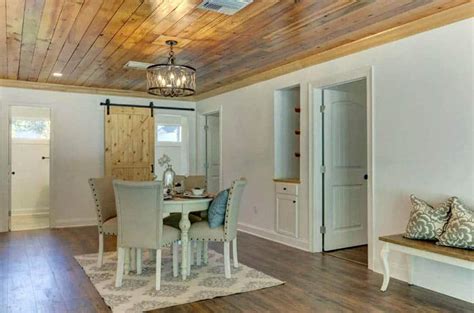 Under a white tongue and groove ceiling fitted with rustic wood beams, mismatched end tables flank a white corner sectional accented with white and black pillows and placed on a gray roven rug at a blond wood frame coffee table. Tongue and Groove (Ceiling, Flooring & Walls) - Designing Idea