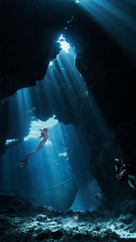 Two People Swimming In An Underwater Cave With Sunlight Streaming
