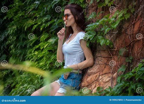 Charming Brunette With Glasses Posing In A Park Near The Leaf Stock