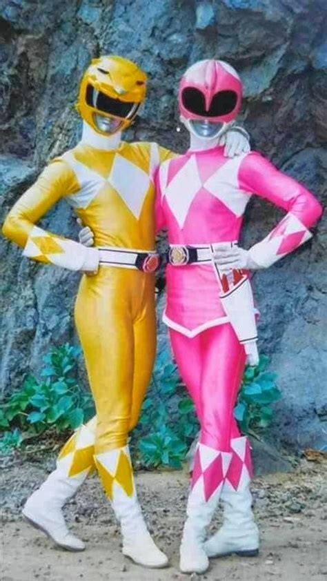Two People In Costume Standing Next To Each Other Near A Rock Wall And