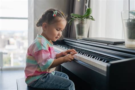 Cute Little Asian Girl Playing Piano At A Music School Stock Photo