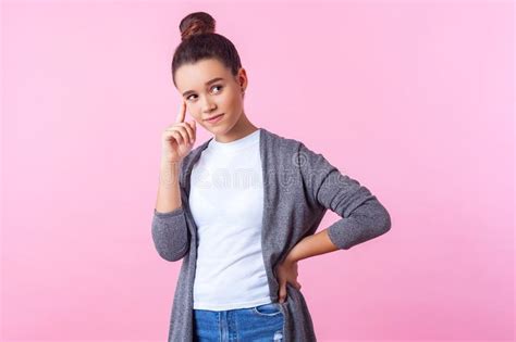 portrait of thoughtful cute brunette teenage girl with bun hairstyle in casual clothes holding