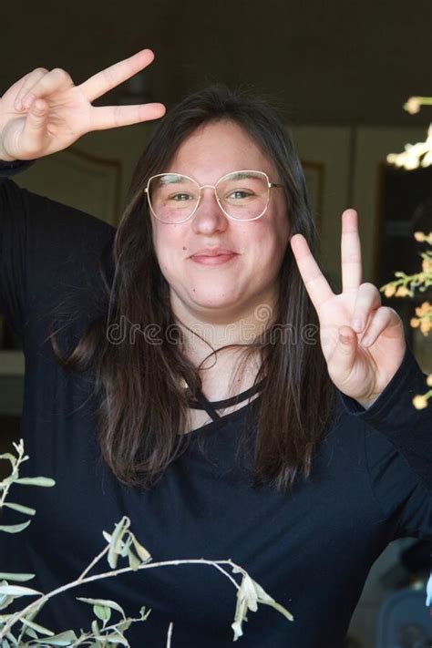 Smiling Girl With Glasses Makes The Victory Sign With Her Hands Stock