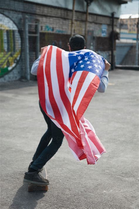 Skateboarder Wearing American Flag As Cape While Riding Del Colaborador De Stocksy Danil