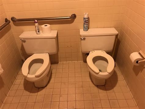 two toilets with their lids open in a public restroom