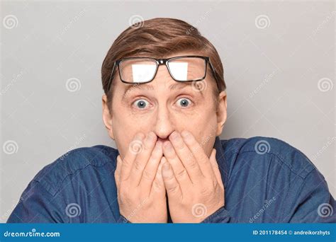 Portrait Of Shocked Frightened Mature Man Covering Mouth With Hands