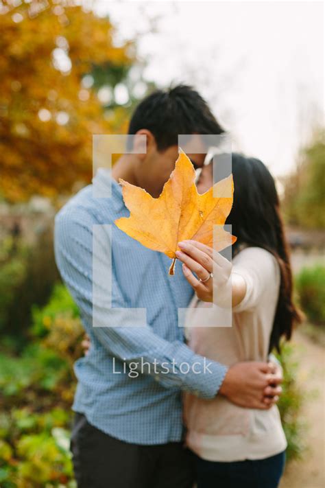man and woman kissing behind a leaf — photo — lightstock