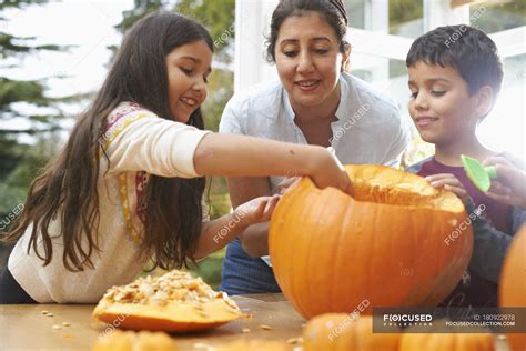 Mother And Children Hollowing Out Pumpkin In Dining Room — Daughter