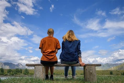 Premium Photo Two Young Women Sitting On Wooden Bench Backs To The
