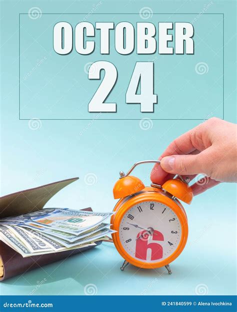 October 24th Hand Holding An Orange Alarm Clock A Wallet With Cash