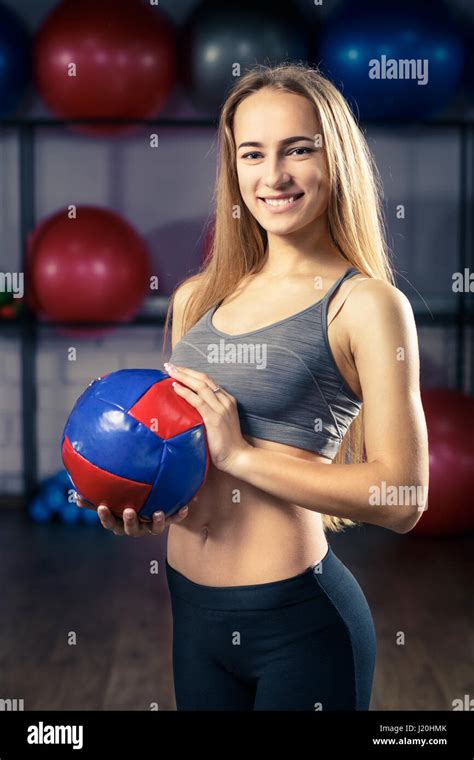 Young Smiling Fitness Girl Standing With Medicine Ball In Gym Warm Color Toned Image Stock