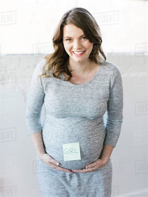 Portrait Of Smiling Pregnant Woman With Adhesive Note On Belly Stock