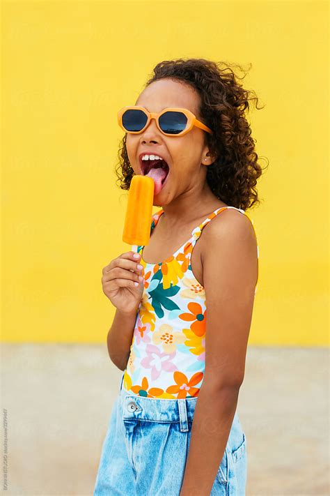 Happy Ethnic Girl Licking Ice Pop By Stocksy Contributor