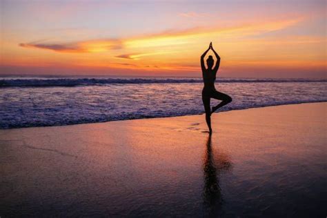 Silhouette Of A Woman Practicing Yoga On The Bali Beach In The Early