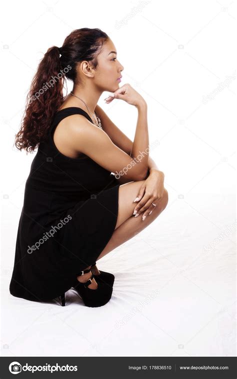 Attractive Latina Woman Squatting Profile In Black Dress Stock Photo By