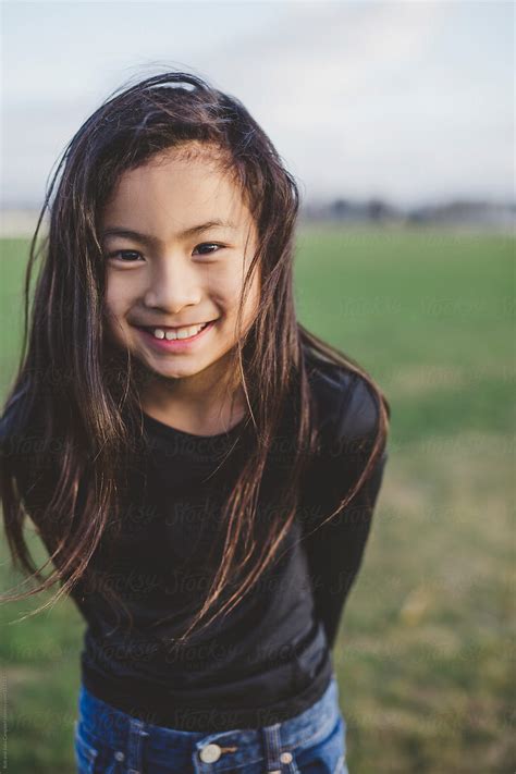 Cute Elementary School Aged Asian Girl Happy In Windy Field Del