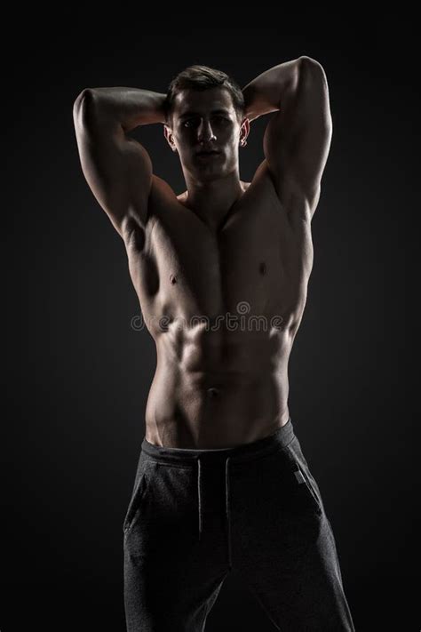 Shirtless Bodybuilder Posing Looking At Camera On Black Background