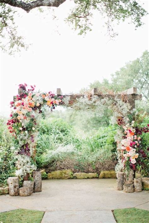 Wooden Arbor Covered With Lush Bold Flowers And With Logs By Its Side