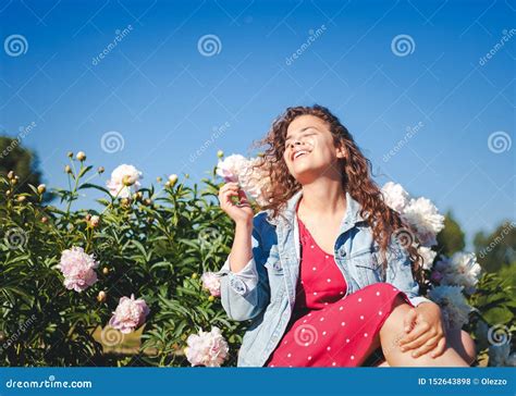 Het Mooie Krullende Meisje Lacht Met Een Charmante Glimlach In De Tuin